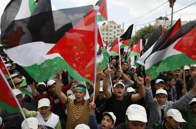 Palestinians wave flags during a rally marking