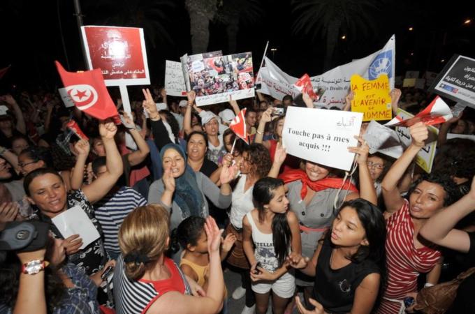 Tunisian women shout slogans and hold po