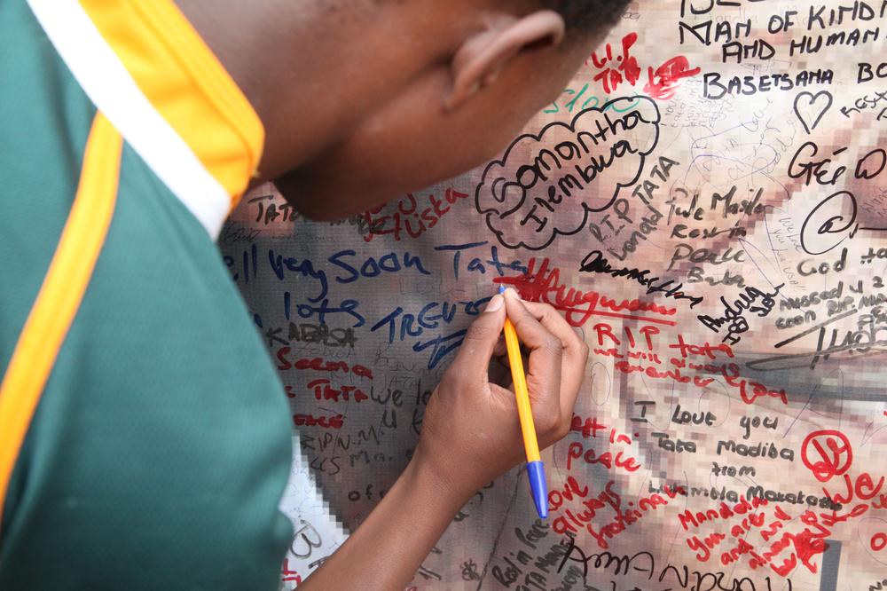 A young boy tries to squeeze a short but sweet (***)We love you(***) onto a Nelson Mandela poster hung outside a museum made in the anti-apartheid hero(***)s honour in the suburb of Soweto, in Johannesburg. Hundreds of mourners took to the streets to mark his passing and celebrate South Africa(***)s most famous man.