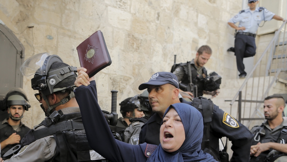A Palestinian woman shouts slogans as she holds a Koran during clashes with Israeli police forces in Jerusalem''s Old City