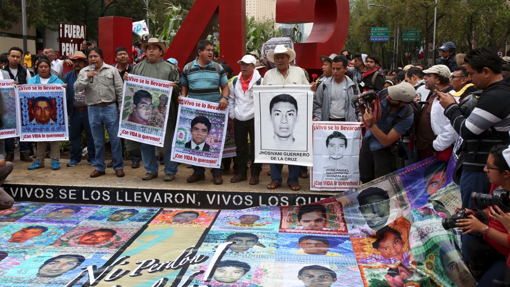 Relatives hold pictures of some of the 43 missing students of Ayotzinapa College Raul Isidro Burgos during a march to mark the first anniversary of their disappearance, in Mexico City