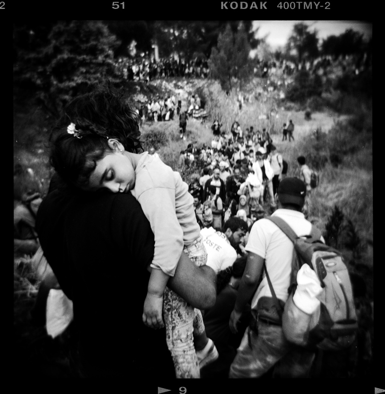 A refugee carries his daughter as he and others make their way to the Greece-Macedonia border – Idomeni, Greece, August 2015 [Giorgos Moutafis] 