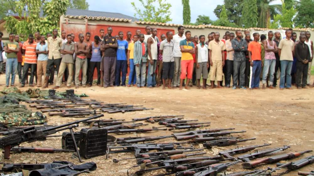 Suspected fighters are paraded before the media by Burundian police near a recovered cache of weapons after clashes in the capital Bujumbura