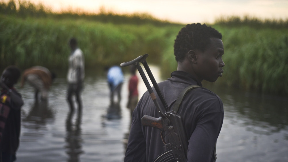 Man with a gun stands watch over displaced people in S Sudan