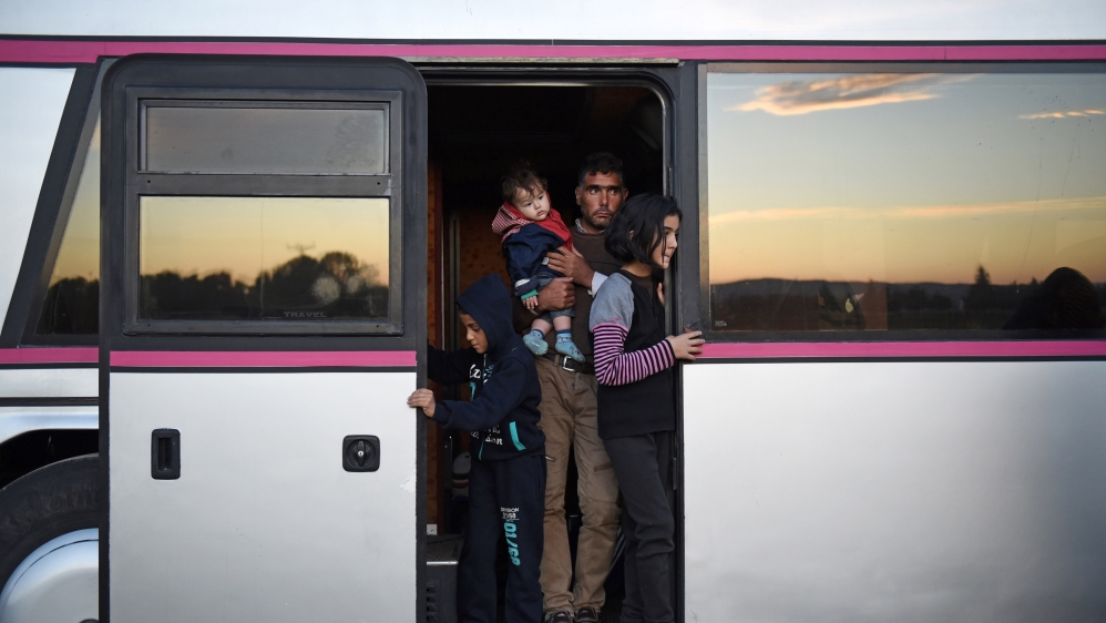 People stand in the doorway of a bus as migrants and refugees wait to pass from the northern Greek village of Idomeni to southern Macedonia