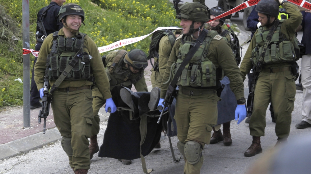 Israeli soldiers carry the body of one of two Palestinian