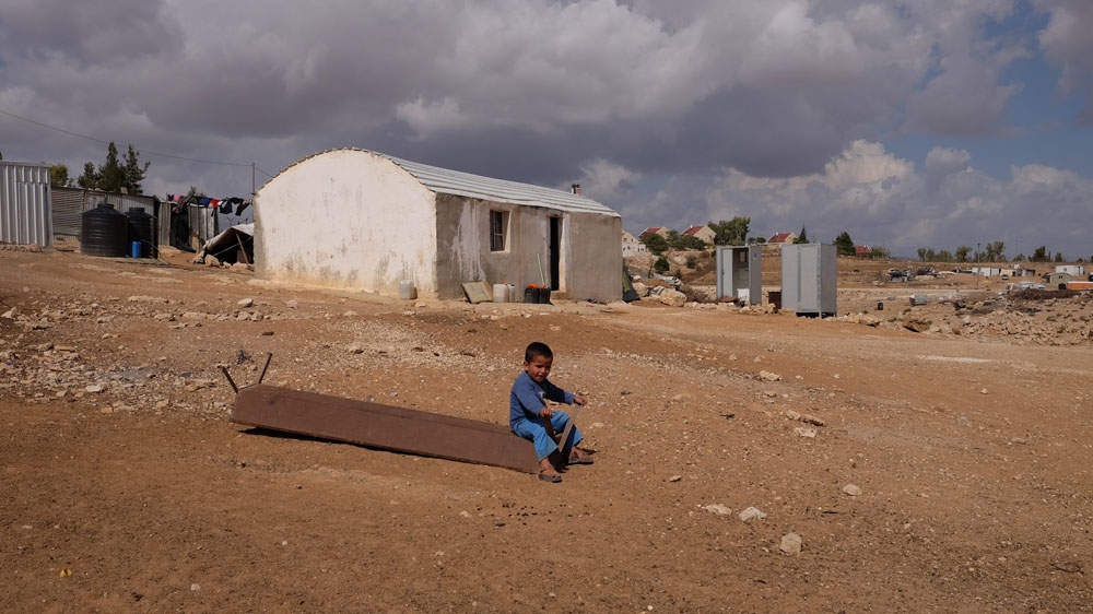 Suleiman Hathaleen's grandchild plays on a discarded trough. On April 6, 35 people were made homeless when Israeli authorities demolished six structures in Umm el-Khair  [Dalia Hatuqa/Al Jazeera]