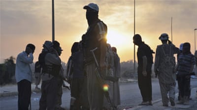 ISIL fighters stand guard at a checkpoint in the northern Iraq city of Mosul [REUTERS]