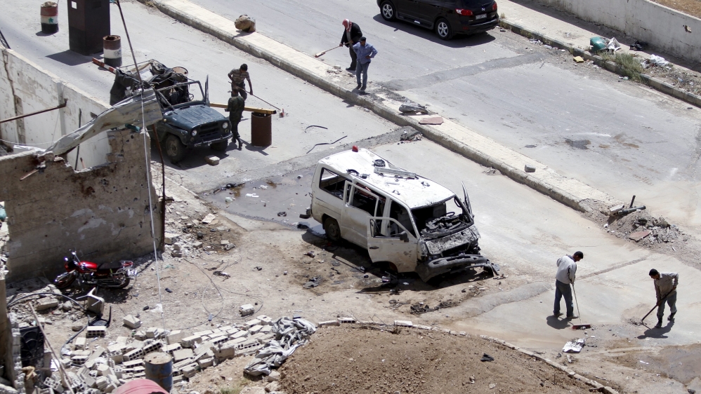 Workers clean a street at the site of a car bomb on the outskirts of the Sayeda Zeinab district south of Damascus