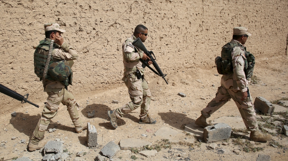 Iraqi soldiers walk in a village of Mahana some 60 km south of Mosul