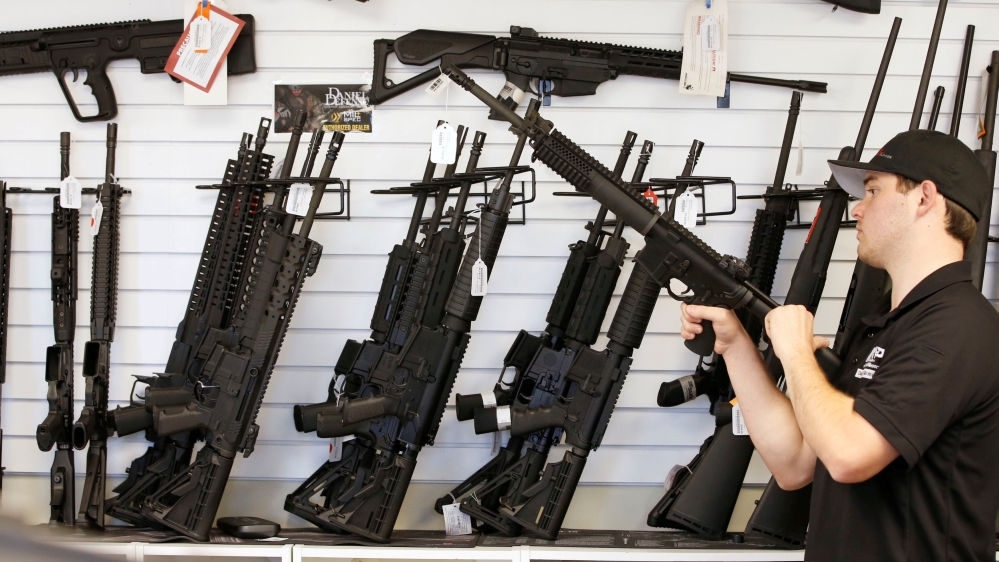Salesman Ryan Martinez clears the chamber of an AR-15 at the "Ready Gunner" gun store In Provo