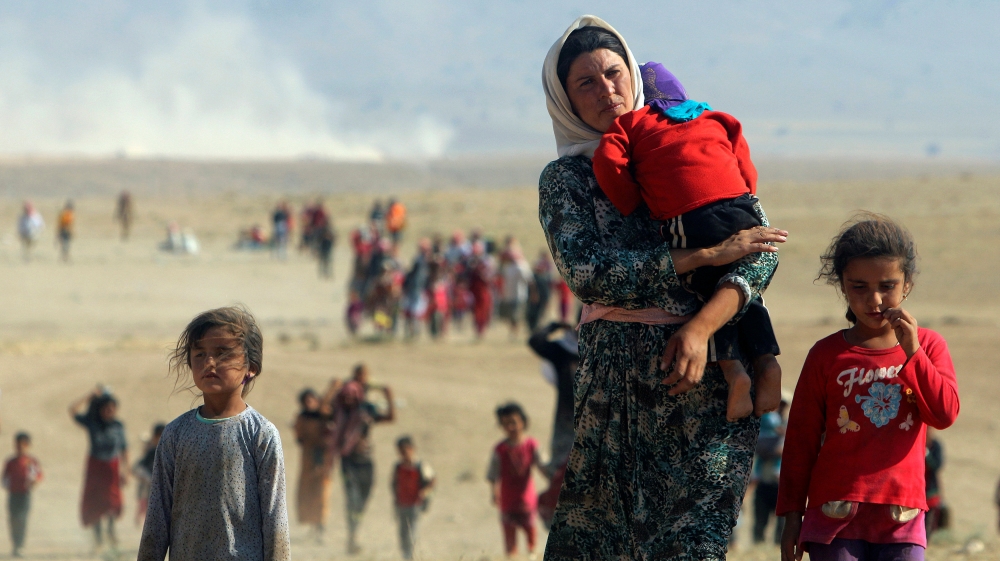 Displaced people from the minority Yazidi sect, fleeing violence from forces loyal to the Islamic State in Sinjar town walk towards the Syrian