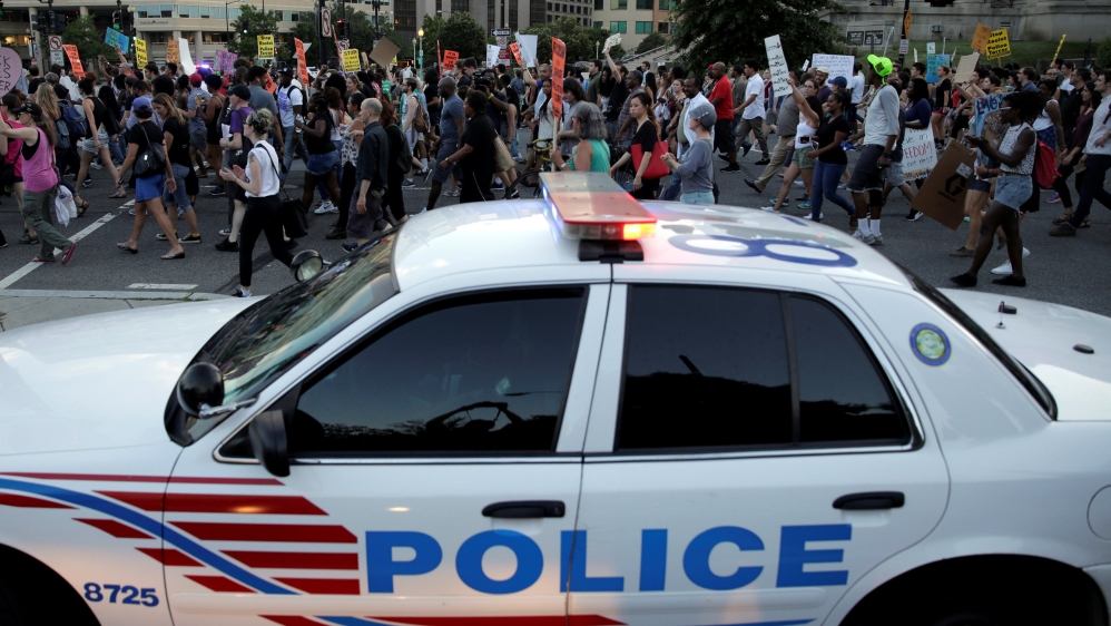 Demonstrators with Black Lives Matter march past a Metropolitan police officer blocking traffic during a protest in Washington