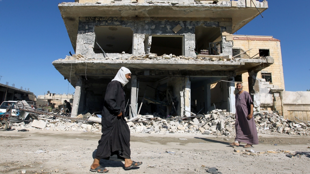 Men walk along a site hit by airstrikes in the rebel held town of Atareb in Aleppo province