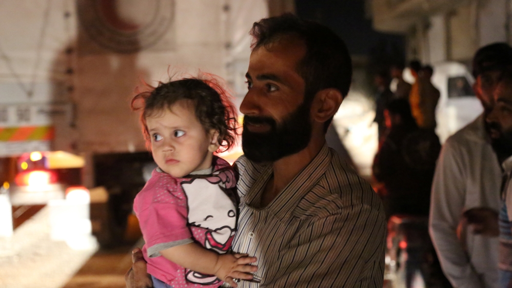 A man holds a child as he stands near a convoy carrying food supplies to deliver to the Syrian rebel-held town of Daraya in this handout picture provided by the World Food Programme