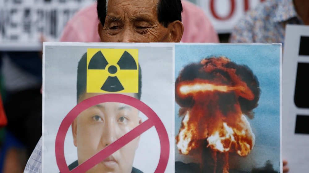 A protester holds a banner depicting defaced North Korean leader Kim Jong Un during an anti-North Korea rally in central Seoul