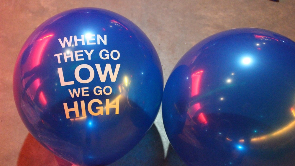 Blue balloons read what Michelle Obama said at the Democratic Convention in July: “When they go low, we go high.”