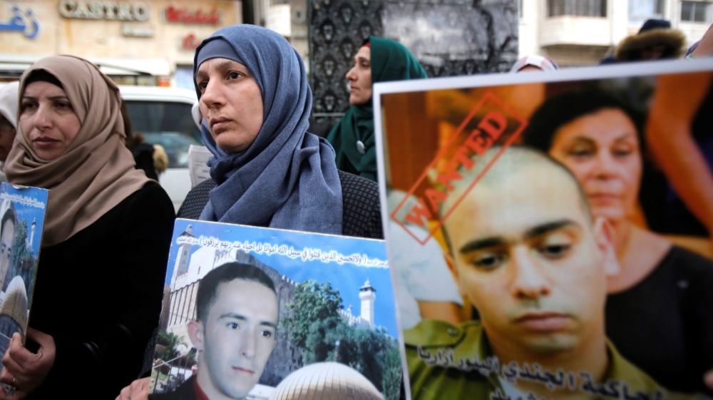 The mother of Sharif holds his poster as another woman holds a poster of Azaria [File: Mussa Qawasma/Reuters]