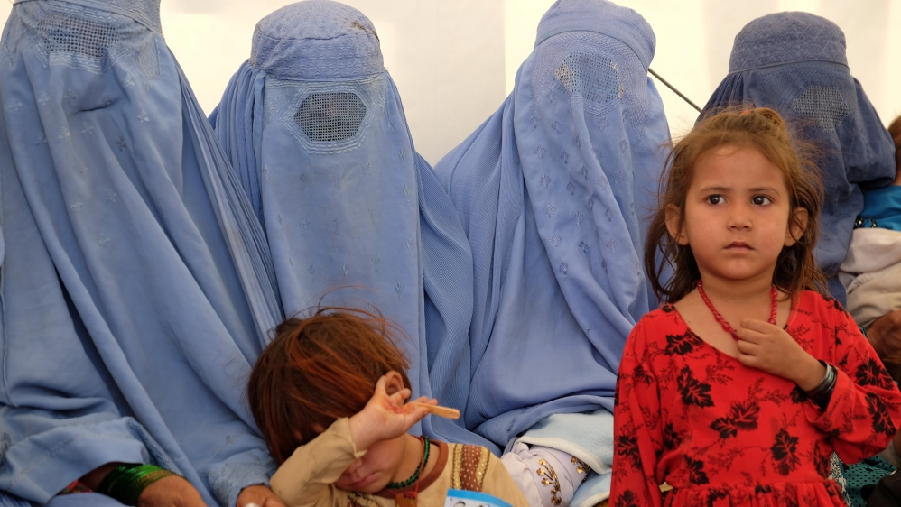 Afghan women, who were living as refugees in Pakistan, wait with their children at a humanitarian aid centre after their return, in Torkham, Afghanistan
