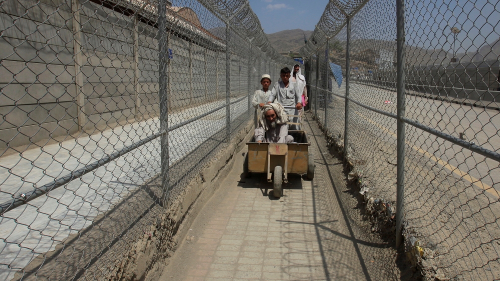 Men coming from Afghanistan move down a corridor between security fences at the border post in Torkham, Pakistan