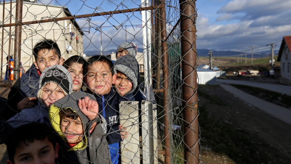 Roma children stand behind a fence near the so called "Sheffield Square" in the town of Bystrany