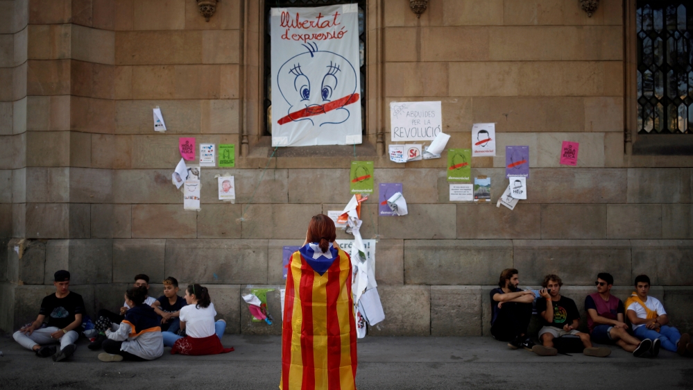 A Canadian tourist takes a picture with an Estelada draped around her shoulders before a political meeting in favor of the banned October 1 independence referendum in Barcelona