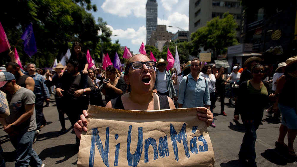 A woman marches holding a sign that reads in Spanish “Not one more” in Mexico City