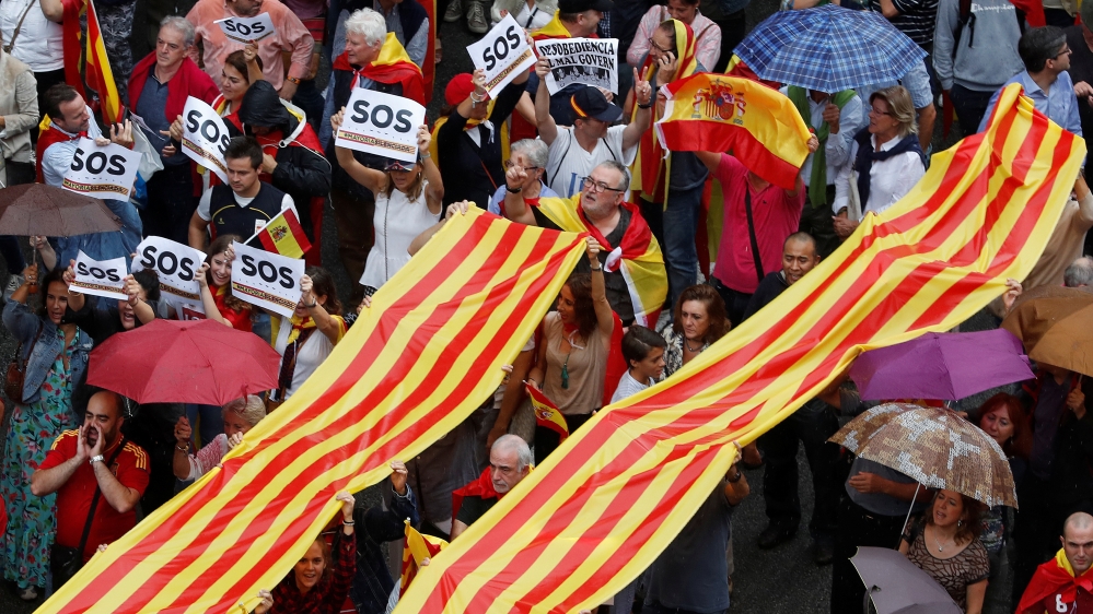 People hold a Catalan flag, known as Senyera, as they march during a demonstration to show support for a unified Spain a day before the banned October 1 independence referendum, in Barcelona