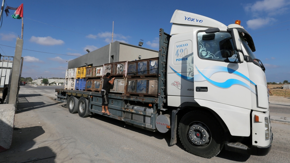 Palestinian man rides on a truck carrying fruits as it arrives at Kerem Shalom crossing in Rafah in the southern Gaza Strip