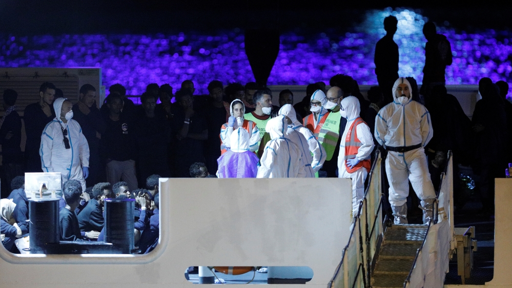 Migrants wait to disembark from the Italian coast guard vessel "Diciotti" at the port of Catania