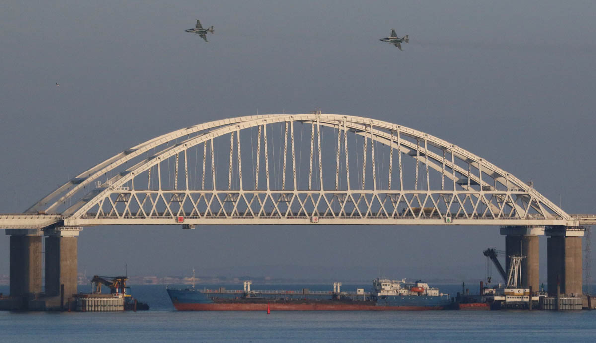 Russian jet fighters fly over a bridge connecting the Russian mainland with the Crimean Peninsula with a cargo ship beneath it after three Ukrainian navy vessels were stopped by Russia from entering t