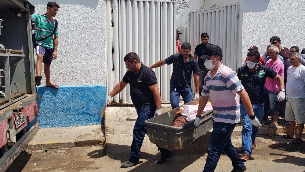 Forensic workers carry a container with a dead body after a shootout between police and bank robbers, in Milagres