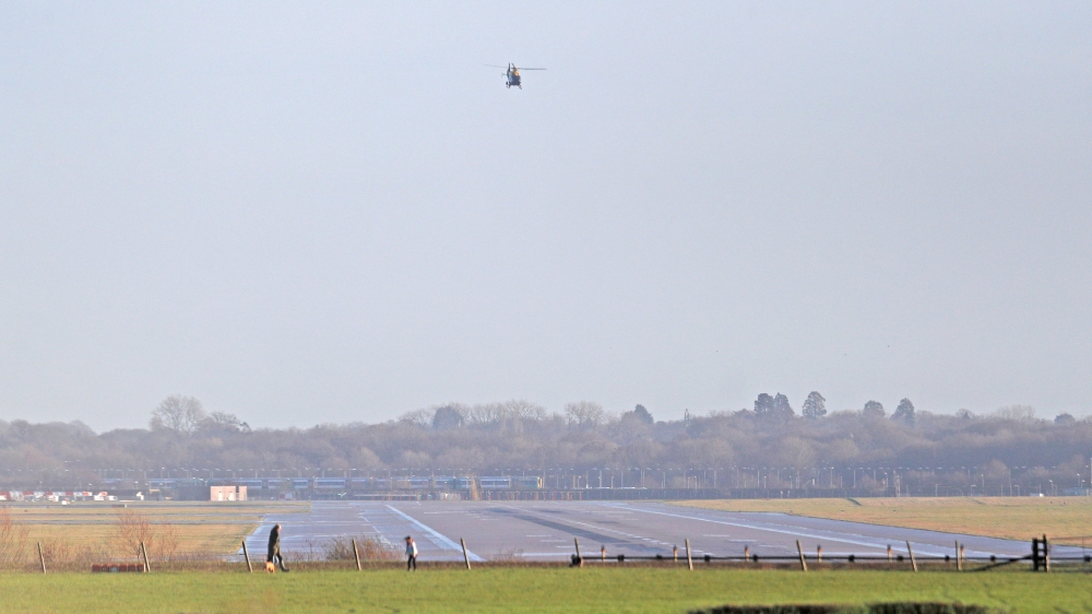A police helicopter flies over the closed runway at Gatwick Airport after drones flying illegally over the airfield forced the closure of the airport, in Gatwick
