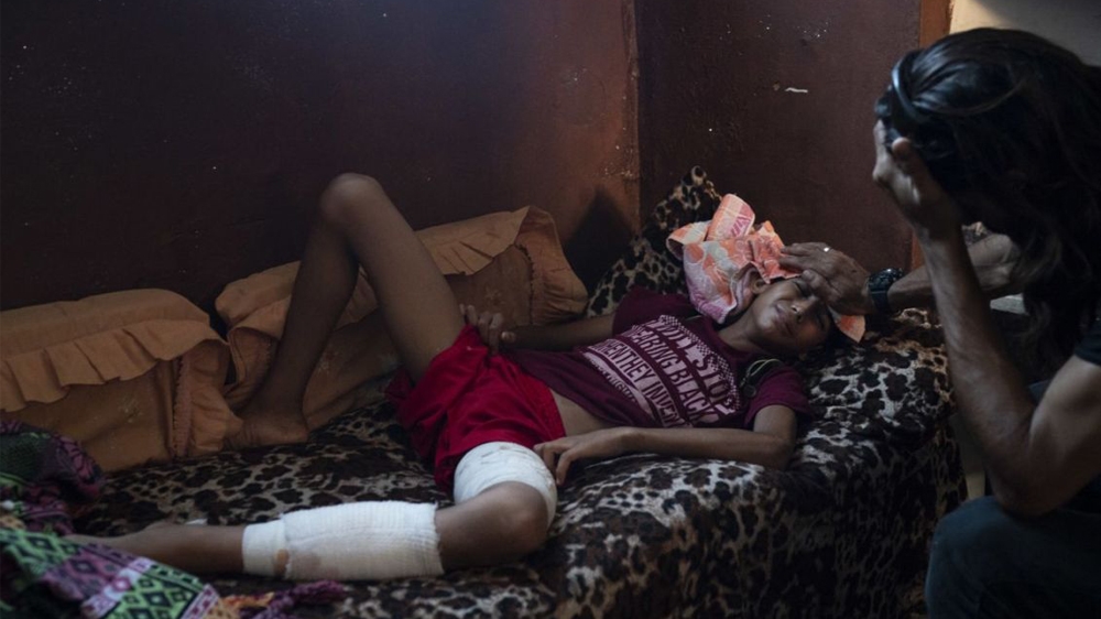 Raed Abu Khader, right, holds a wet cloth on the forehead of his 12-year-old son Mohammed in Gaza City. Mohammed was shot in the leg at one of the demonstrations on Gaza strip’s border with Israel.