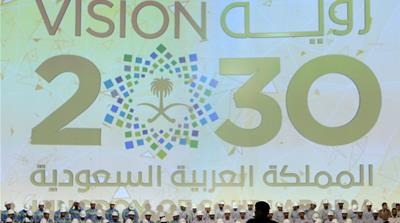 Large banner shows Saudi Vision for 2030 as a soldier stands guard before the arrival of Saudi King Salman at the inauguration of several energy projects in Ras Al Khair