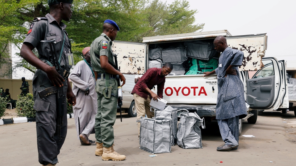 Police members oversee Ad-hoc staff loading boxes onto a truck during the distribution of election materials at the INEC office in Yola