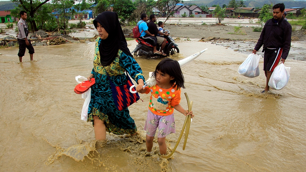 Residents carry their belongings as they wade through flood water in Sentani, near Jayapura, Papua province, Indonesia, 18 March 2019. At least 79 people were killed and 43 missing as a flash floods h