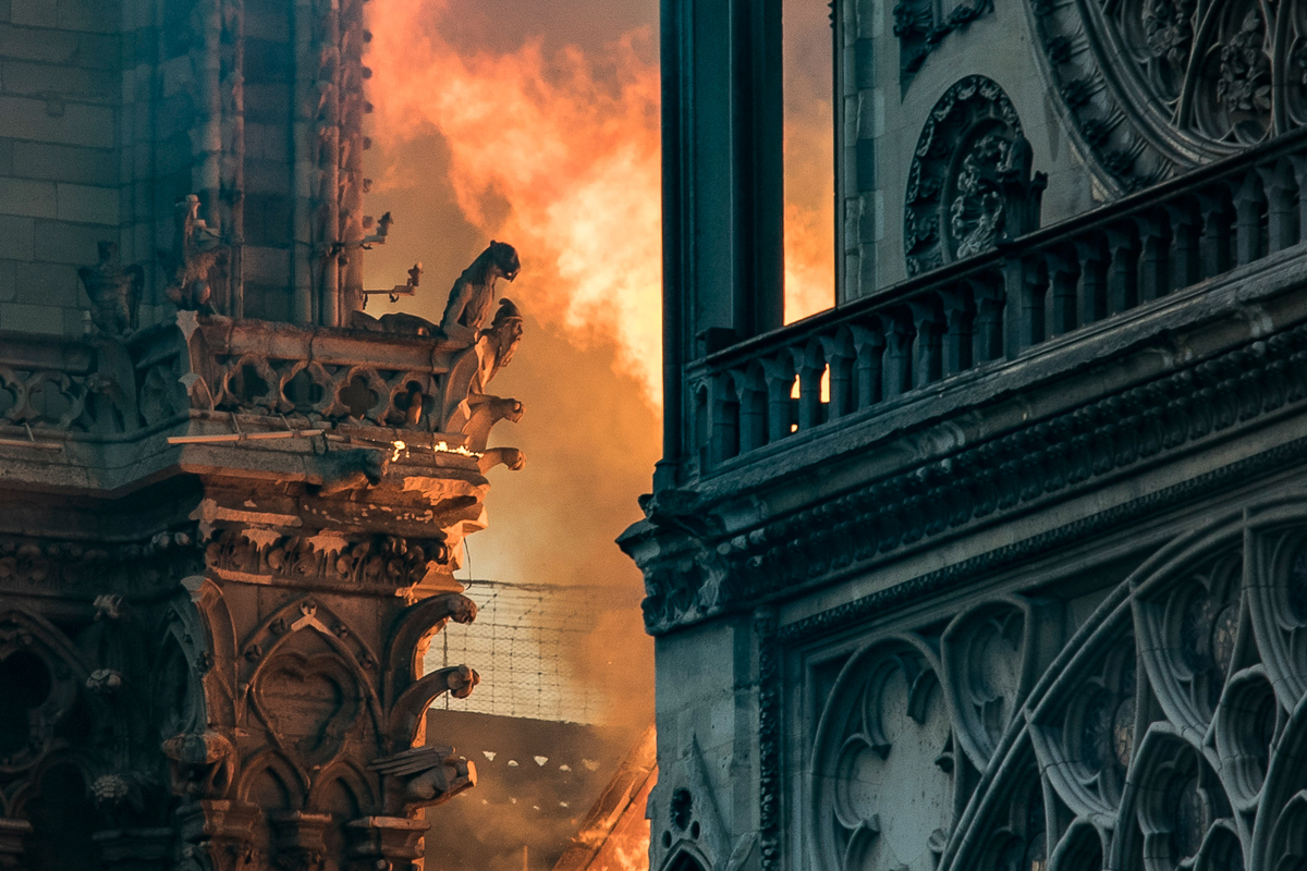 Flames and smoke billow around the gargoyles decorating the roof and sides of the Notre-Dame Cathedral in Paris on April 15, 2019. - A huge fire swept through the roof of the famed Notre-Dame Cathedra
