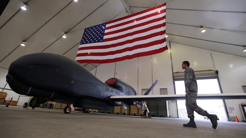 A U.S. Air Force maintainer makes his way into a hangar packed with RQ-4 Global Hawk aircraft, at an Air Force base in Arabian Gulf