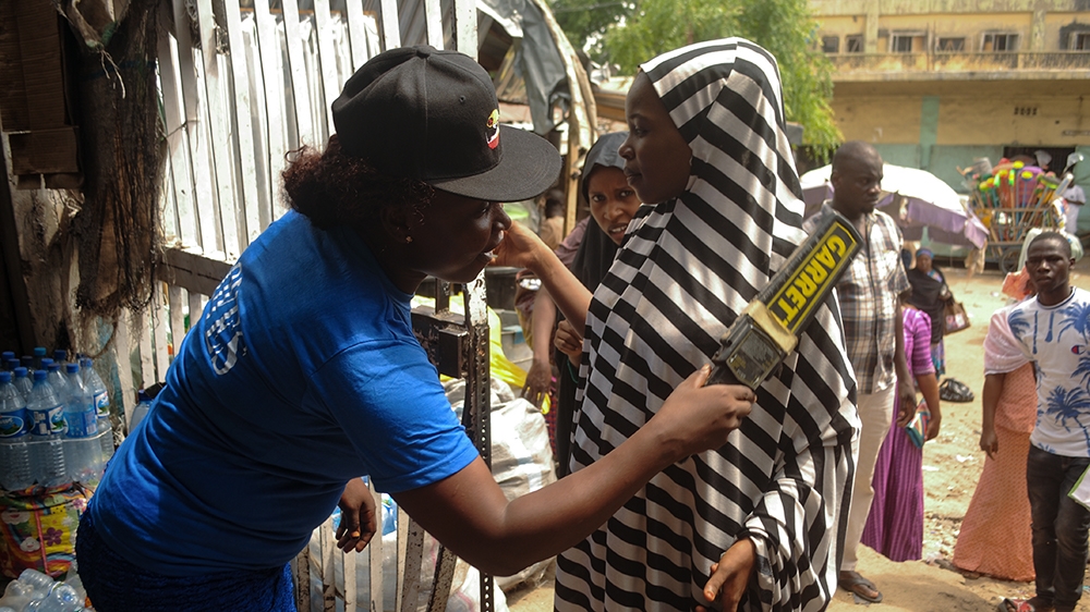 Kaje Komi searches a woman entering a local market in Maiduguri, northeast Nigeria