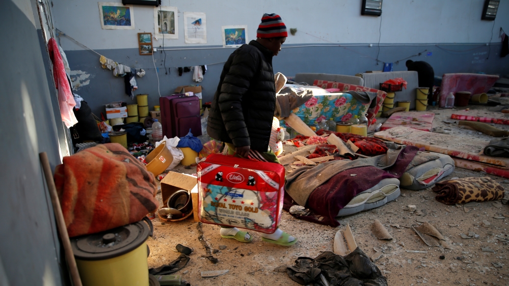 A migrant carries his belongings at a detention centre for mainly African migrants, that was hit by an airstrike in the Tajoura suburb of Tripoli