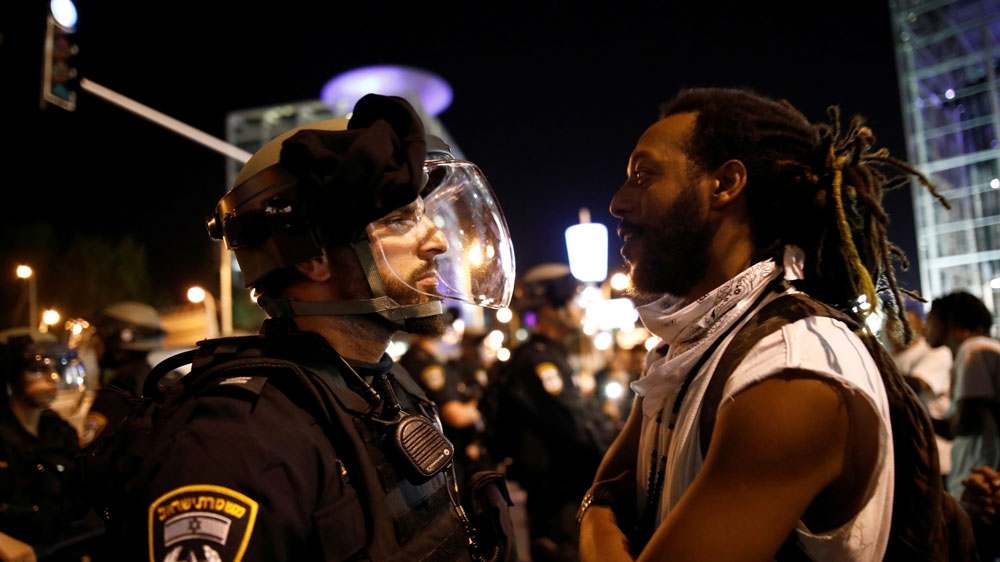 A protester stands opposite to a policeman during a protest in Tel Aviv
