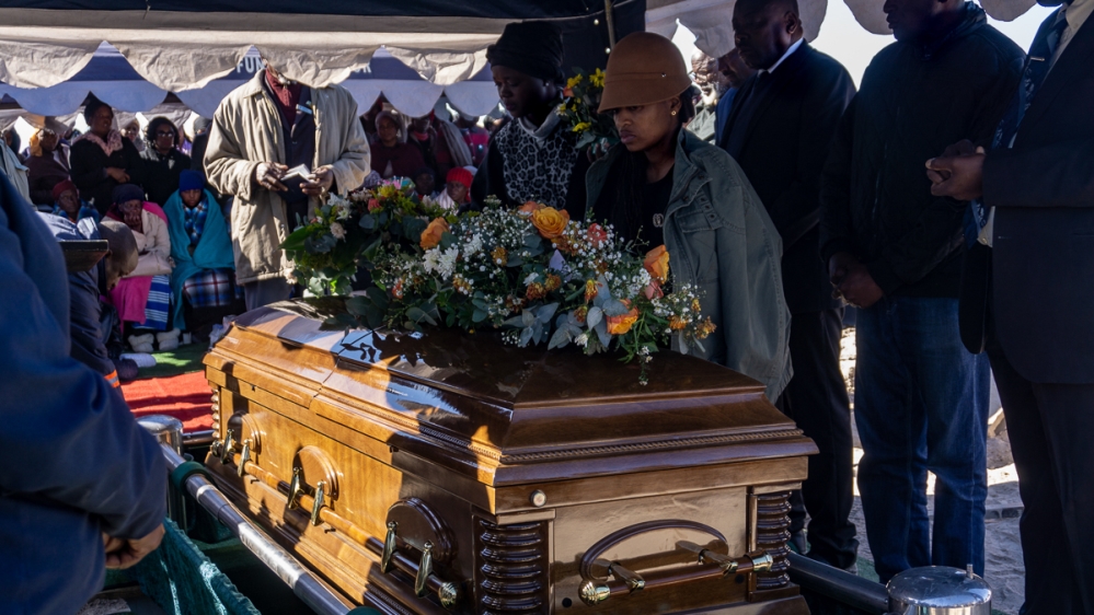 Ngakaemang Roy Chombo’s granddaughter lays flowers on his coffin as the former wildlife park ranger is laid to rest