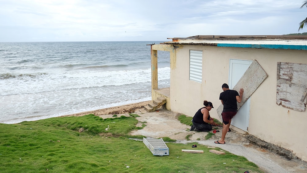 A couple boards up the door of their beachfront house as Tropical Storm Dorian approaches in Yabucoa, Puerto Rico
