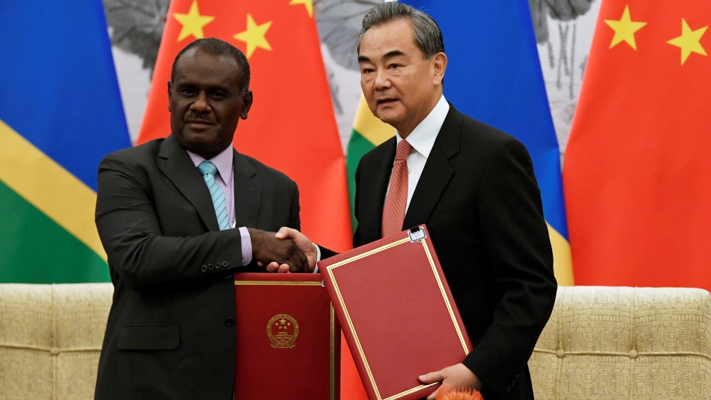 Chinese State Councilor and Foreign Minister Wang Yi shakes hands with Solomon Islands Foreign Minister Jeremiah Manele during a ceremony in Beijing