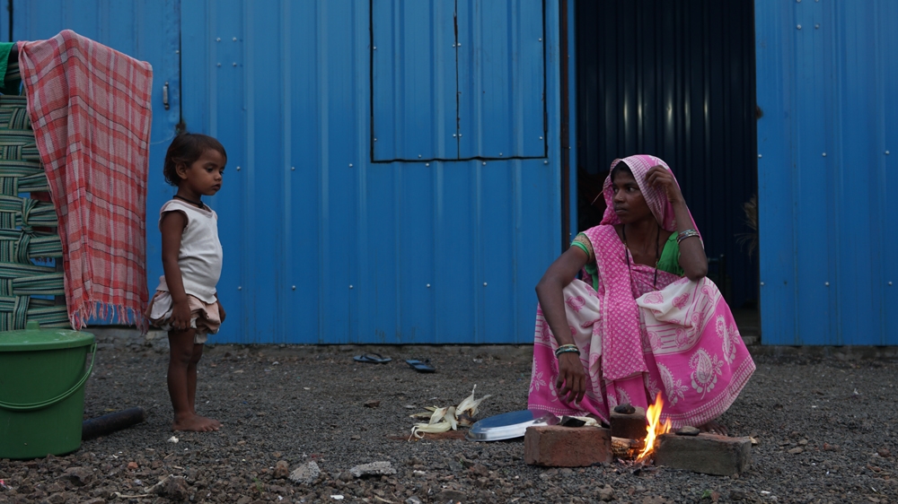 Unhappy with the state-supplied meal ration, a mother roasts corn to feed her family at a temporary rehabilitation camp in Barwani
