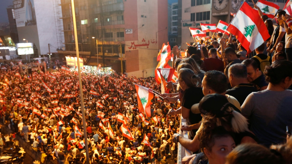 Demonstrators carry national flags as they stand on a bridge during an anti-government protest along a highway in Jal el-Dib, Lebanon