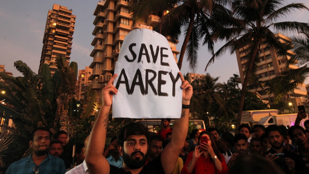 A man displays a placard at a promenade during a protest demanding that MMRCL not cut trees to build a train parking shed for an upcoming subway line, in Mumbai
