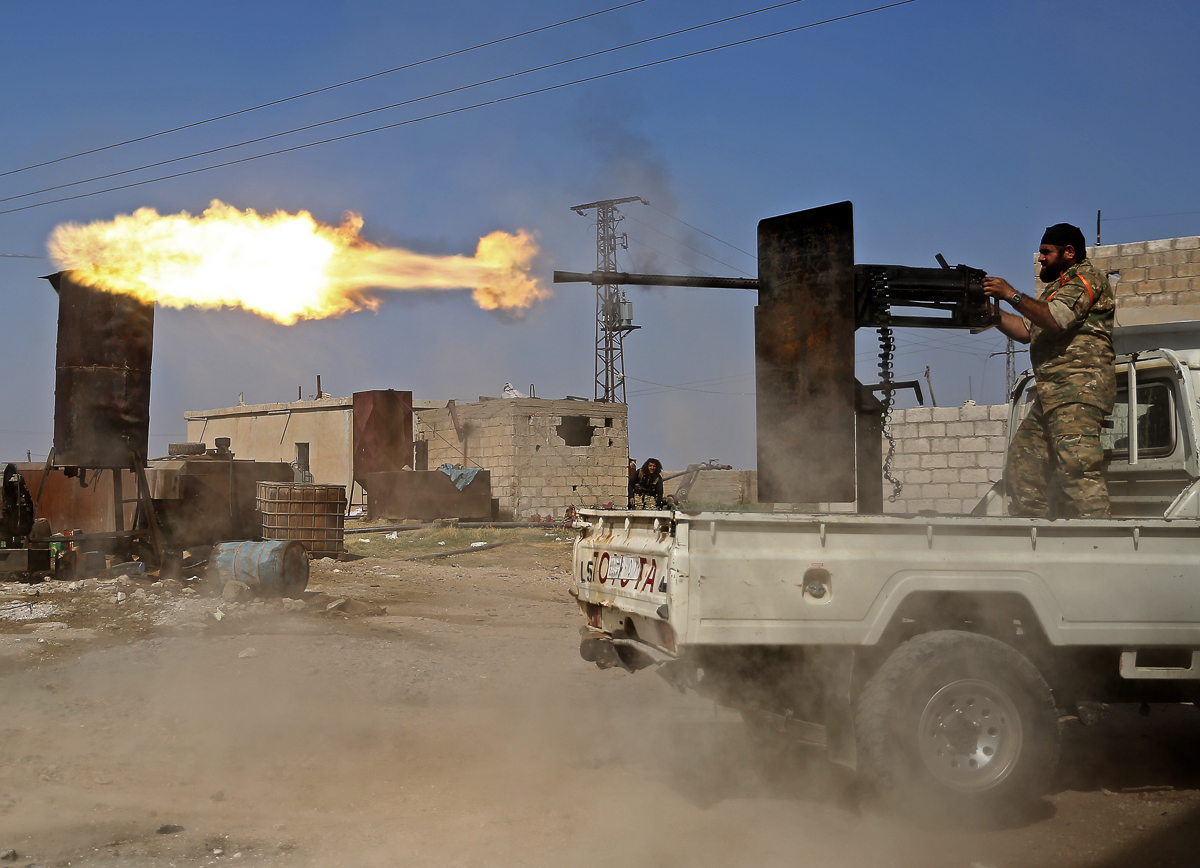 A Turkish-backed Syrian fighter fires during clashes in the border town of Ras al-Ain on October 13, 2019, as Turkey and its allies continue their assault on Kurdish-held border towns in northeastern