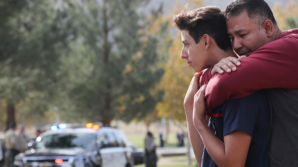 Marco Reynoso, right, hugs his son, 11th-grader Dylan Reynoso, after reuniting near Saugus High School